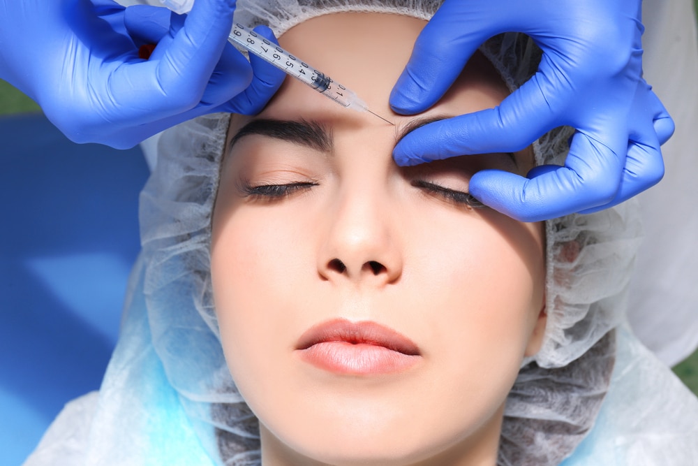 Woman receiving dermal filler injections in her eye brows to enhance her brow lift.